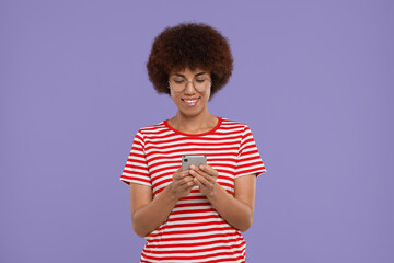 Happy young woman with smartphone on purple background