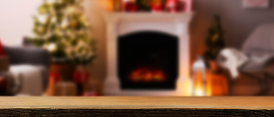 Empty wooden table in room with Christmas tree and fireplace. Banner with space for design