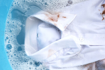 Dirty choclate stain on white shirt in water with detergent water dissolution, washing cloth - obrazy, fototapety, plakaty