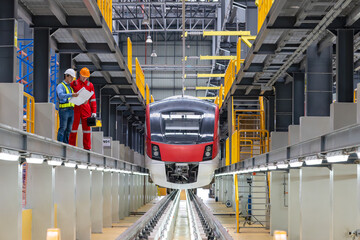 Electric train technician engineer checking controls system for security functions in maintenance infrastructure plant of sky train, public transportation vehicle,Teamwork management concept.