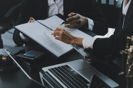 Business and lawyers discussing contract papers with brass scale on desk in office. Law, legal services, advice, justice and law concept picture with film grain effect