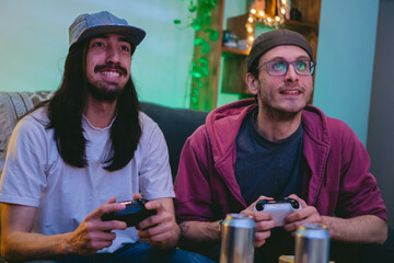 two young Latin man friends playing with a console in an apartment while drinking beer