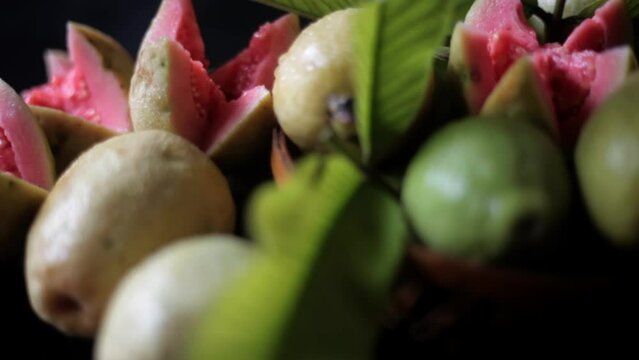 Cinematic dolly shot of ripe red guava fruit on a black shiny glossy wooden surface. Desi amrud or jamrukh (Psidium guajava) on a wooden surface. High-quality HD footage.