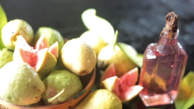 High-quality footage of red ripe guava fruit in a basket along with its extracted oil in a bottle, HD footage.