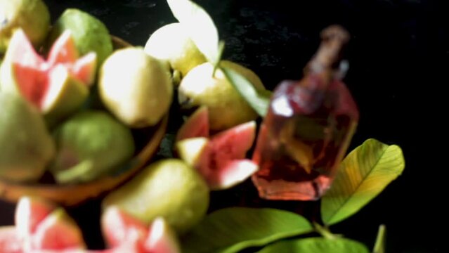 High-quality footage of red ripe guava fruit in a basket along with its extracted oil in a bottle, HD footage.