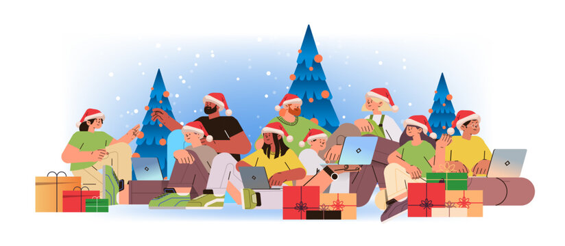 mix race men women in santa hats near decorated christmas tree using laptops social media communication new year holidays celebration