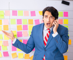 Young handsome employee with many conflicting priorities