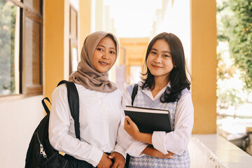Portrait of smiling teenage female students standing together in high school campus