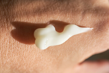 A smear of white moisturizer or sunscreen on a woman's hand.