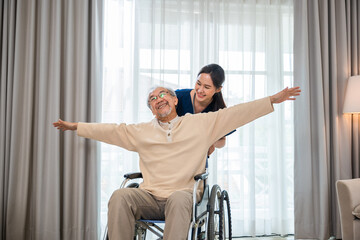 Asian senior retired old man sitting on wheelchair having fun with young woman nurse, Happy curator person doctor pushing and running elderly patient freedom raising arm, sanatorium - obrazy, fototapety, plakaty
