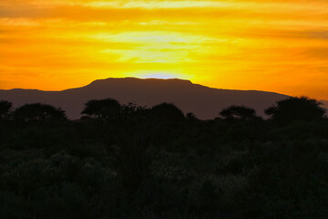 The dusty savanna of Tsavo and the red clay produces fiery sunsets over Tsavo East National Park, Kenya, Africa