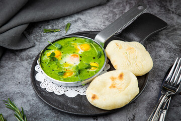 creamy broccoli soup in a frying pan with tortillas against a dark background, side view