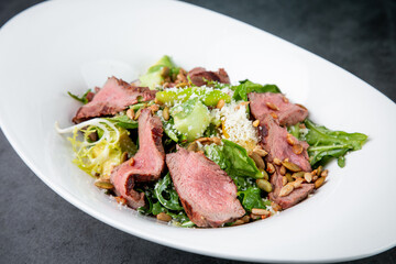 salad with pieces of beef, pistachios, lettuce and cheese side view