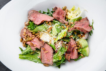 salad with pieces of beef, pistachios, lettuce and cheese side view