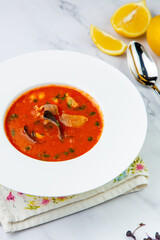 orange cream soup with pieces of meat in a white plate, side view