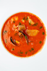orange cream soup with pieces of meat in a white plate, top view