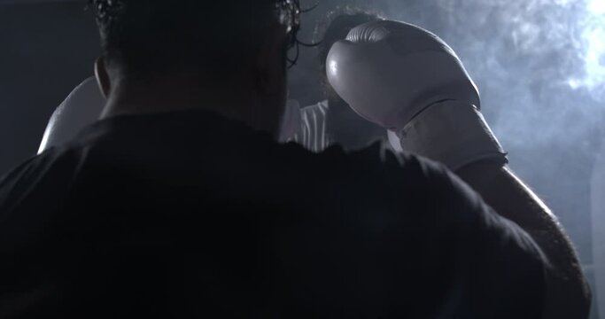 Two fighters facing each inside ring in dramatic lighting stare. fighter wearing boxing glove facing opponent in slow-motion 800 fps