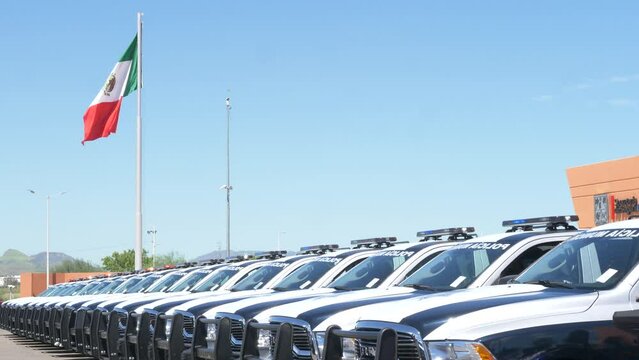 Line formation of Mexican cop cars. Police event with Mexican flag hanging from a pole in the background