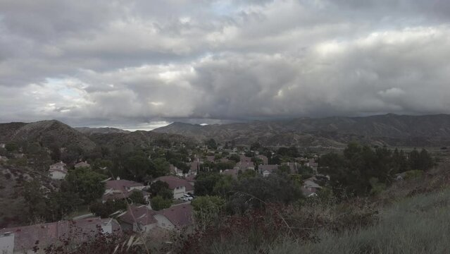 Time lapse footage of the clouds moving over the homes in a residential neighborhood among hills