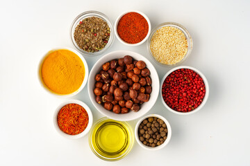 Bowls with spices and cooking ingredients on white background