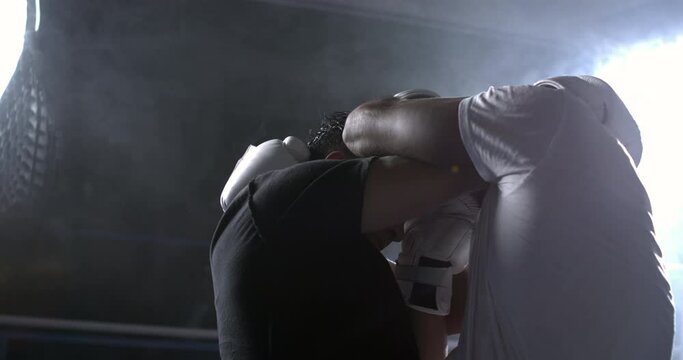 Fighters clinching each other inside boxing ring to prevent opponent to blow punch during dramatic intense confrontation captured in slow-motion