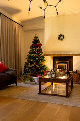 Decorated christmas tree by fireplace in homely living room, copy space