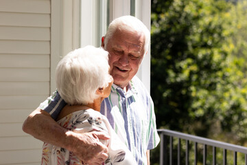 Back view of caucasian senior couple embracing and looking at each other on balcony on sunny day