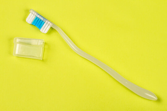 Toothbrush with cap on green background. Modern toothbrush close-up.