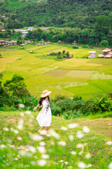 Young happy woman tourist enjoying and relaxing with beautiful landscape view rice paddy field while traveling at Nan, Thailand