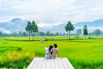 Young happy couple tourist enjoying and relaxing at rice paddy field while traveling at Nan, Thailand
