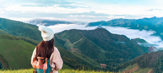 Young woman travelers looking at the sunrise and the sea of mist on the mountain in the morning,...