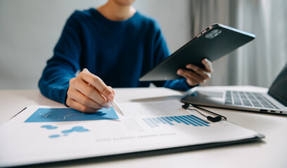 business documents on office desk with laptop and smart phone and graph business diagram and man working at office