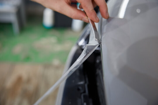 Worker-detailer cutting off excess of polymer protective outer coating closeup