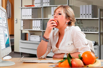 Frau ißt einen Apfel am Arbeitsplatz