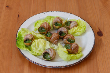 Escargots de Bourgogne (snails) seasoned with butter, parsley, garlic on wooden table
