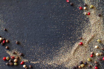 Ground pepper and colored peppercorns on black background, copy space