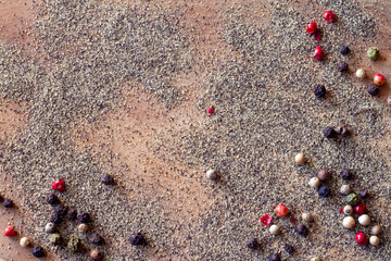 Ground pepper and colored peppercorns on wooden background