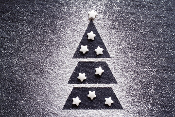 Christmas tree made of flour on black background, sugar stars, creative christmas background