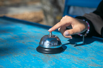 Woman ringing service bell on the table.