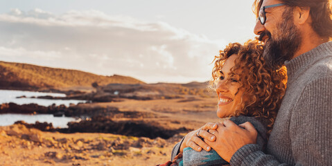 Happy couple hugging and enjoying travel destination. together with smile and serene expression. One man embrace woman from behind. Concept of traveler vacation lifestyle. Sunny portrait of people - obrazy, fototapety, plakaty