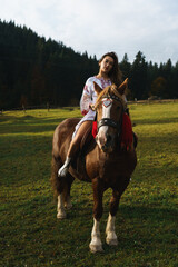 Young women ride horses in national Ukrainian dresses in the Carpathian mountains. Photo session...