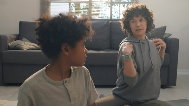Medium shot of Caucasian mother with curly hair guiding her son, teaching yoga exercises