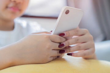 Happy young asian woman relax on comfortable couch at home texting messaging on smartphone.