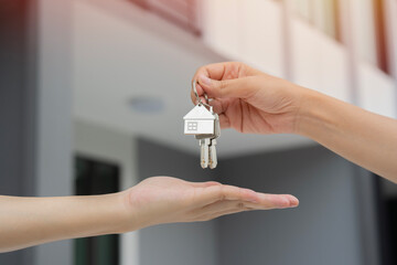 Selective focus of hand of real estate agent giving house key to new home buyer. Mortgage concept.