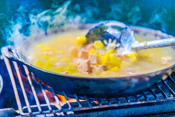 Hot cooked vegetables and fish in a pan in selective focus. Steam rises. Cook food. Fresh fish soup.