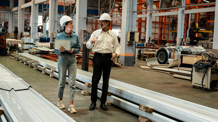 Factory manager or executive with assistant make visit factory tour and inspect heavy steel...