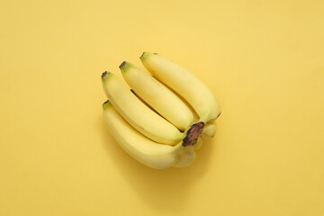 Top view of bunch of ripe yellow bananas isolated on yellow background. Bananas are rich in...