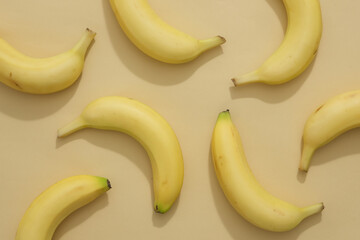Scene for advertising product with banana ingredient with ripe yellow bananas displayed on beige background. Top view, minimalist style. Natural ingredient for skin care