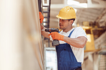 Male worker using cordless electric drill at construction site