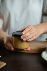 Peanut butter in woman hands in the kitchen.